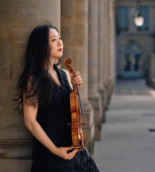 Anna Lee with her violin in a classical colonnade