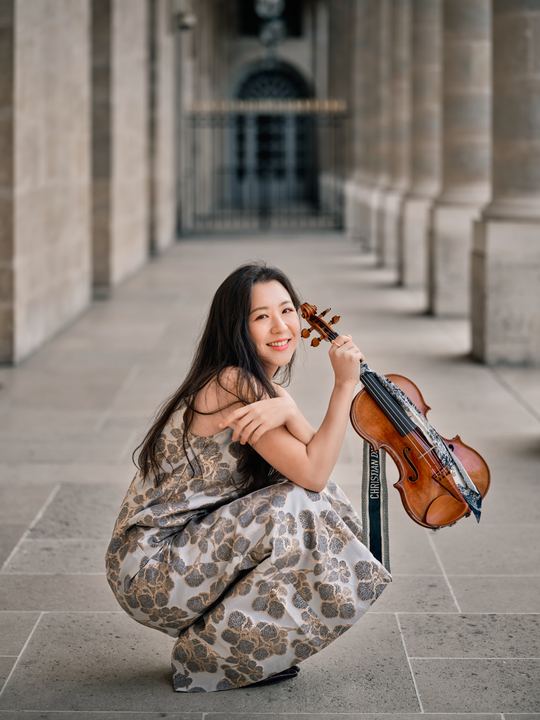 Anna Lee with her violin in a colonnade