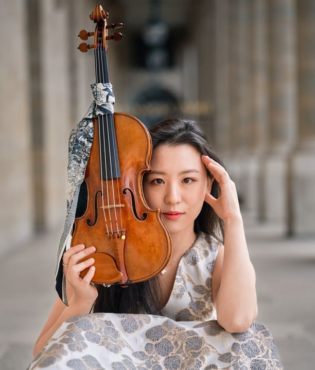 Close portrait of Anna Lee holding the scroll of her violin