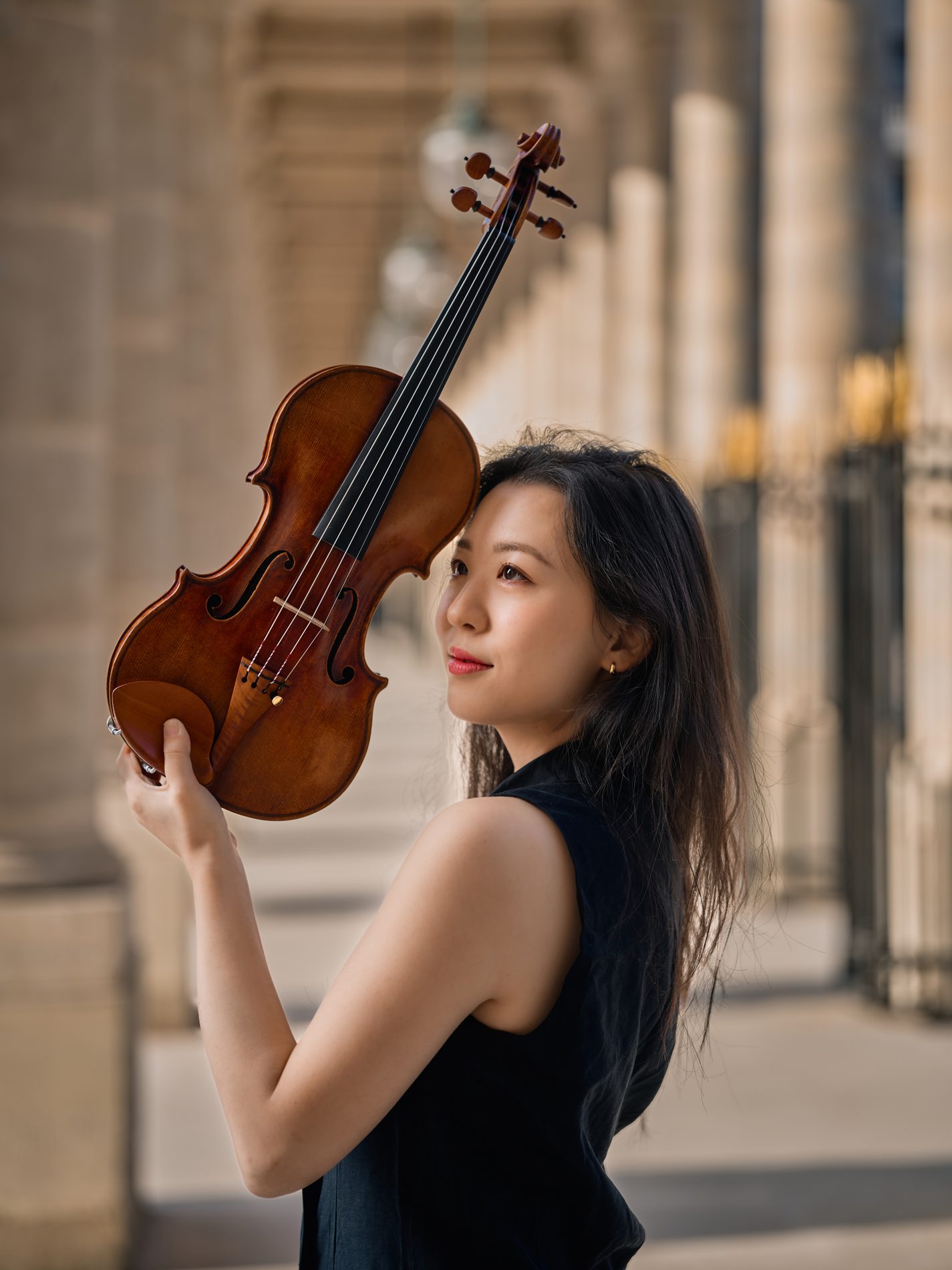 Portrait of Anna Lee with her violin against a warm colonnade
